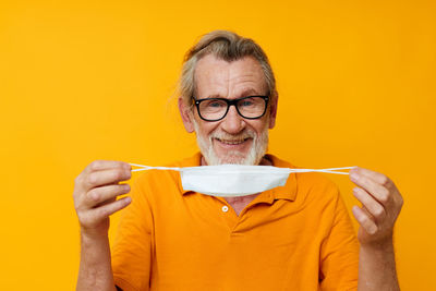 Portrait of young man drinking coffee against yellow background