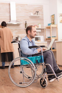 Disabled man using laptop in kitchen at home