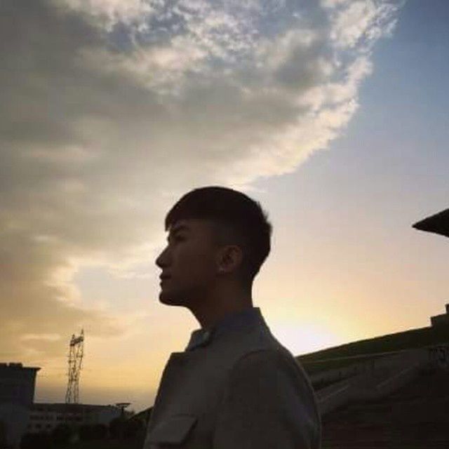 sky, lifestyles, headshot, sunset, low angle view, young adult, person, portrait, looking at camera, standing, young men, leisure activity, cloud - sky, built structure, waist up, front view, building exterior, architecture