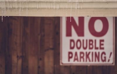 Icicles on roof against warning sign