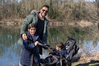 Father with stroller and two children is walking along the aare river in springtime. 