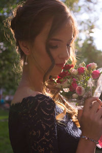 Side view of woman holding flowers during sunset