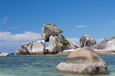 Scenic view of rocks in sea against blue sky