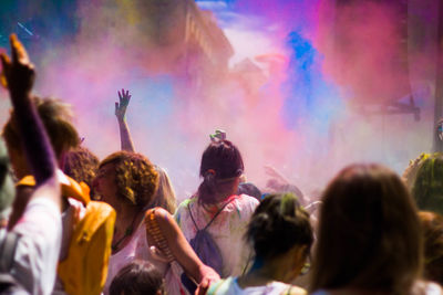 Crowd with arms raised playing holi