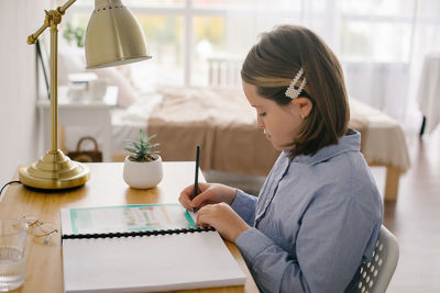 Side view of young woman using laptop at home