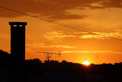 Silhouette electricity pylon against sky during sunset