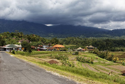 Houses on field by mountain against sky