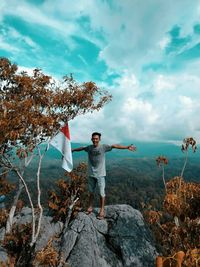 Full length of man standing on rock against sky