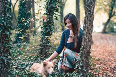 Young woman with dog on tree trunk