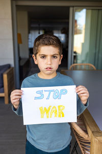 Little kid showing stop war on a paper. ukraine russia war concept.