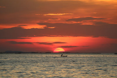 Sunset on red sky back evening cloud over horizon sea and fishing boat