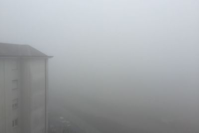 Scenic view of foggy weather against sky during winter