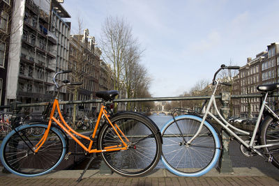 Bicycle parked by building against sky