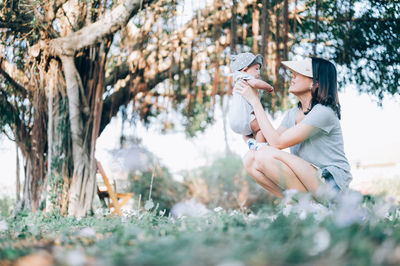 Woman sitting on field by tree