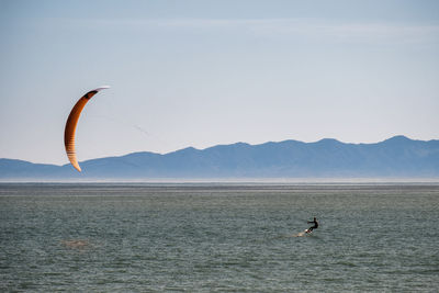 Man kiteboarding in sea against sky