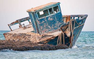 Abandoned boat in sea against clear sky