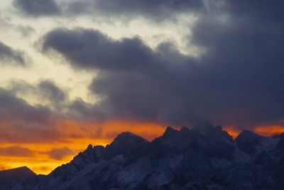 Scenic view of dramatic sky over mountains during sunset