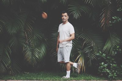 Full length portrait of man standing against palm trees