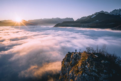 High angle view of man standing on mountain ridge rising above the clouds, hallein, austria