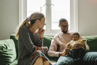 Parents with baby girl sitting on sofa