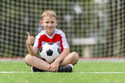 Happy boy playing soccer on land