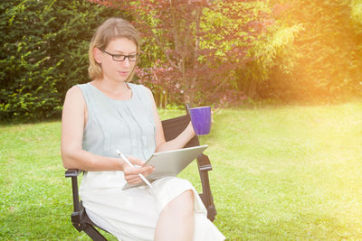 Young woman using digital tablet while sitting in park