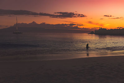 Scenic view of a person swimming in sea at dusk