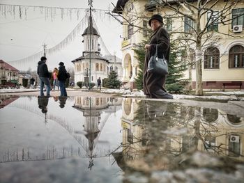 Reflection of people on puddle in city