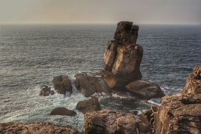 Rocks on sea shore against sky