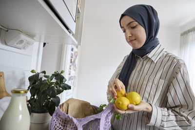 Woman in headscarf unpacking groceries at home