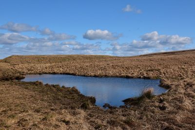 Scenic view of lake in moorland against blue sky