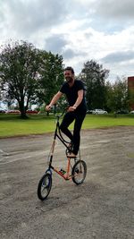 Young man riding folding bicycle on footpath