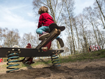 Low angle view of boy jumping against trees