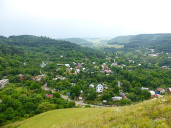 Scenic view of trees and houses on field against sky