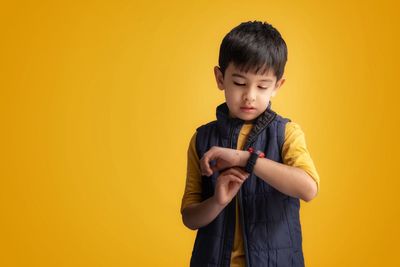 Portrait of cute girl standing against yellow background