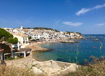 Buildings by sea against blue sky