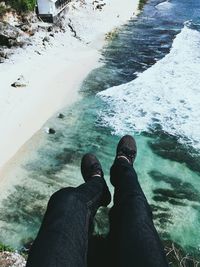 Low section of man standing in sea