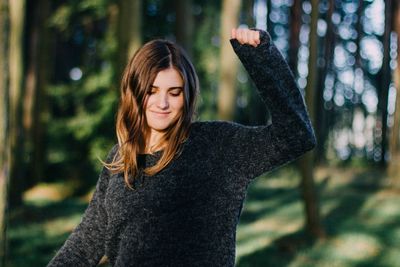 Smiling young woman standing in forest