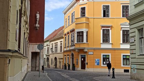 Rear view of woman walking on street amidst buildings in city