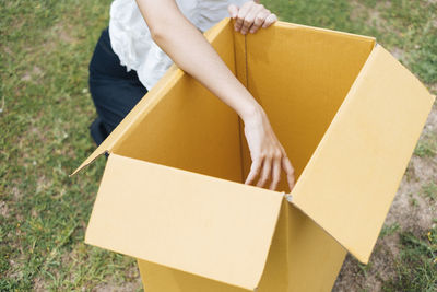 Midsection of woman with cardboard box on grass