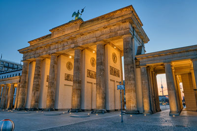 The back side of the famous brandenburg gate in berlin before sunrise with the television tower
