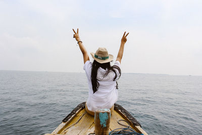 Rear view of woman standing in sea against sky