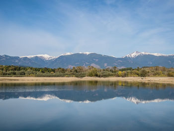 Scenic view of lake by mountains against sky