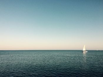 Sailboat sailing in sea against clear sky