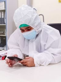Man wearing protective suit using mobile phone