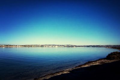 Calm sea against clear blue sky