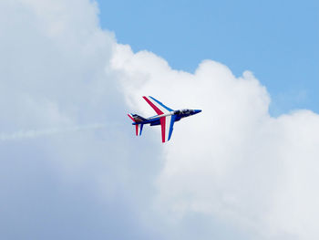 Low angle view of military airplane flying in clouded blue sky