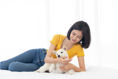 Portrait of a smiling young woman sitting against wall