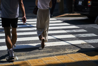 Low section of people walking on zebra crossing