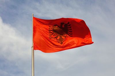 Low angle view of red albanian flag against sky